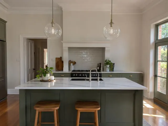 Two glass pendant lights over a kitchen island in a renovated home with green cabinetry in Willoughby