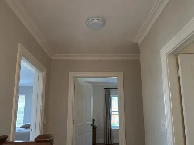 Ceiling smoke alarm in a painted hallway with white trim and doorways in Willoughby